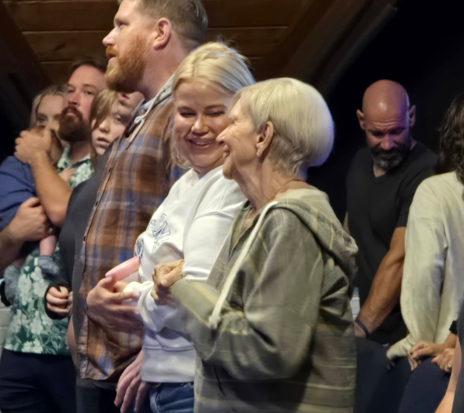 Smiling people of all ages worshiping together at The River Bible Church